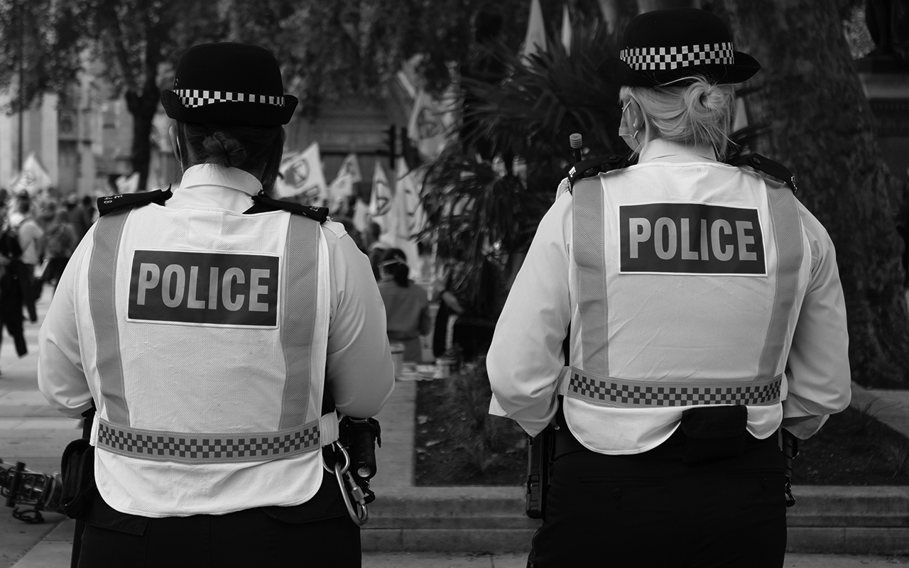 Two London police officers in high-visibility vests with their backs to the camera