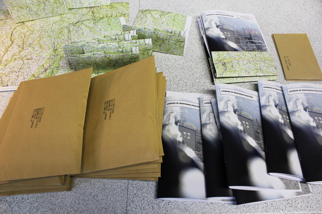 Booklets and folded maps and envelops laid out beside a host of brown sealed mailers.